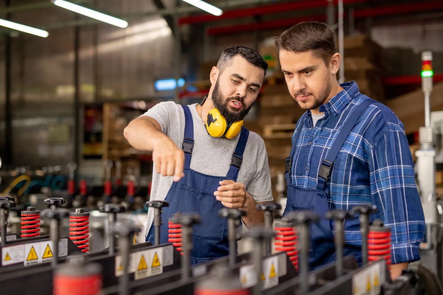 Junger Auszubildender sieht sich Industrieanlagen an und hört dem Vorgesetzten zu